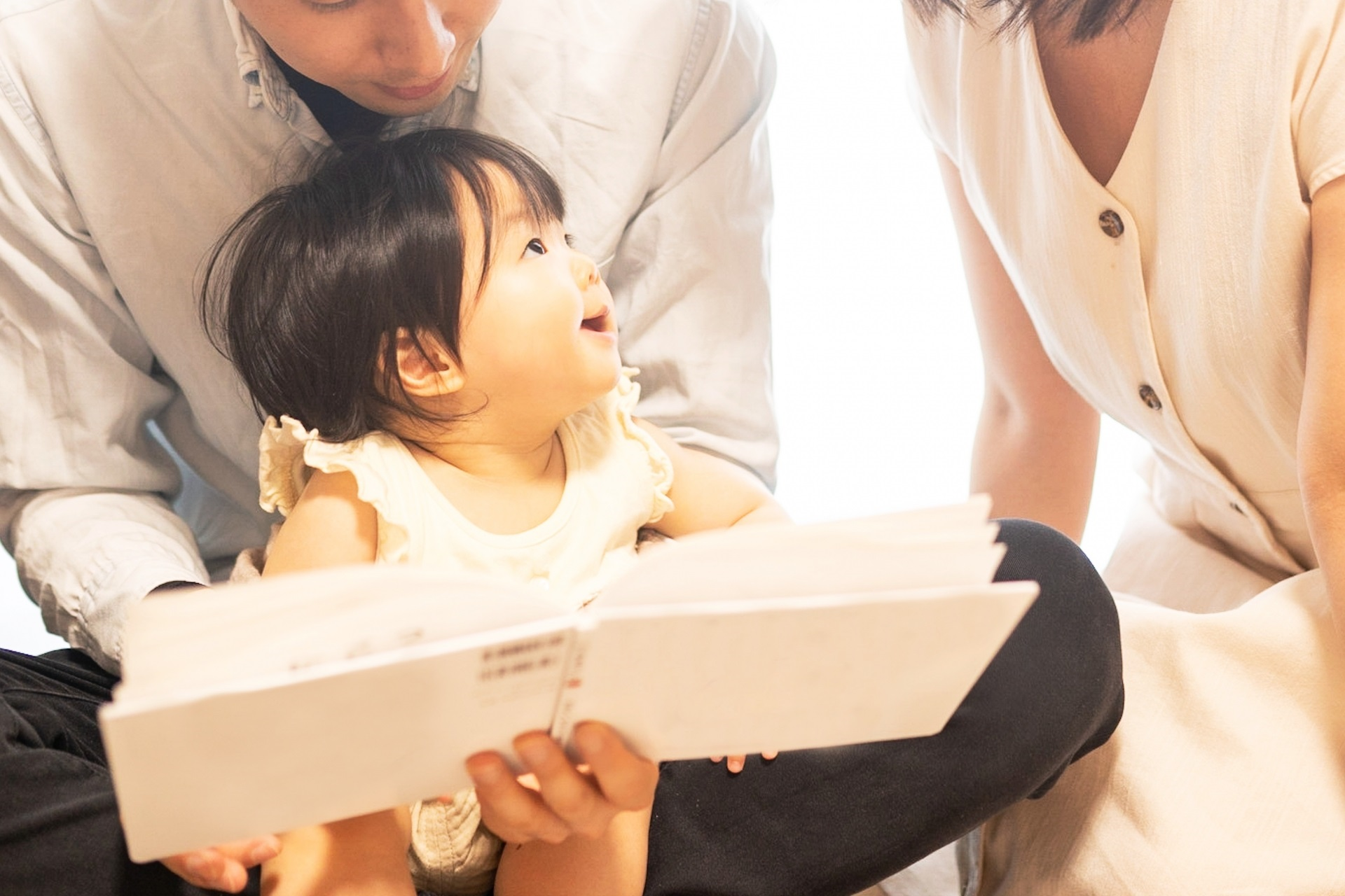我が子に本を見せる両親