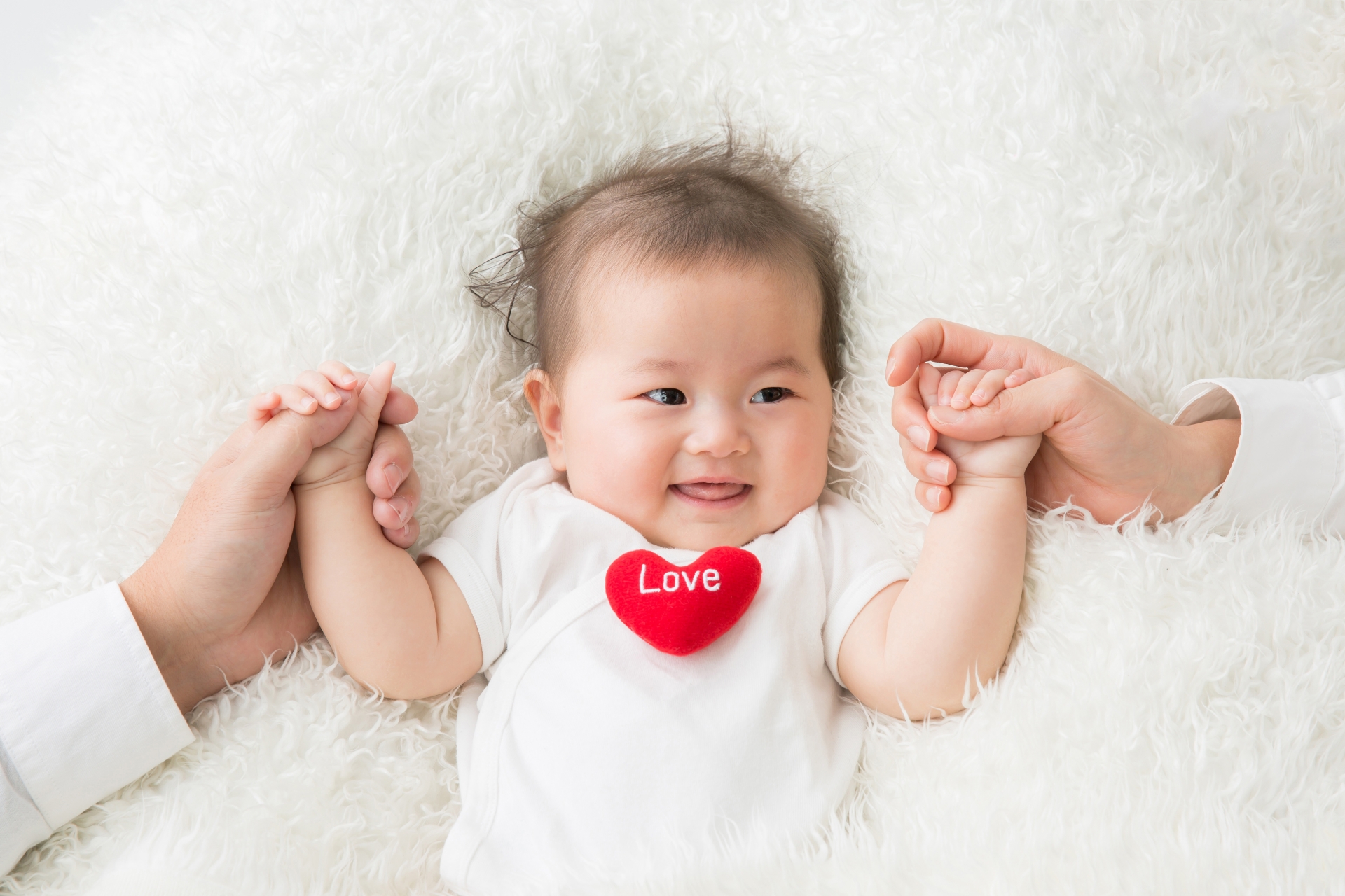 両親に手を握られている赤ちゃん