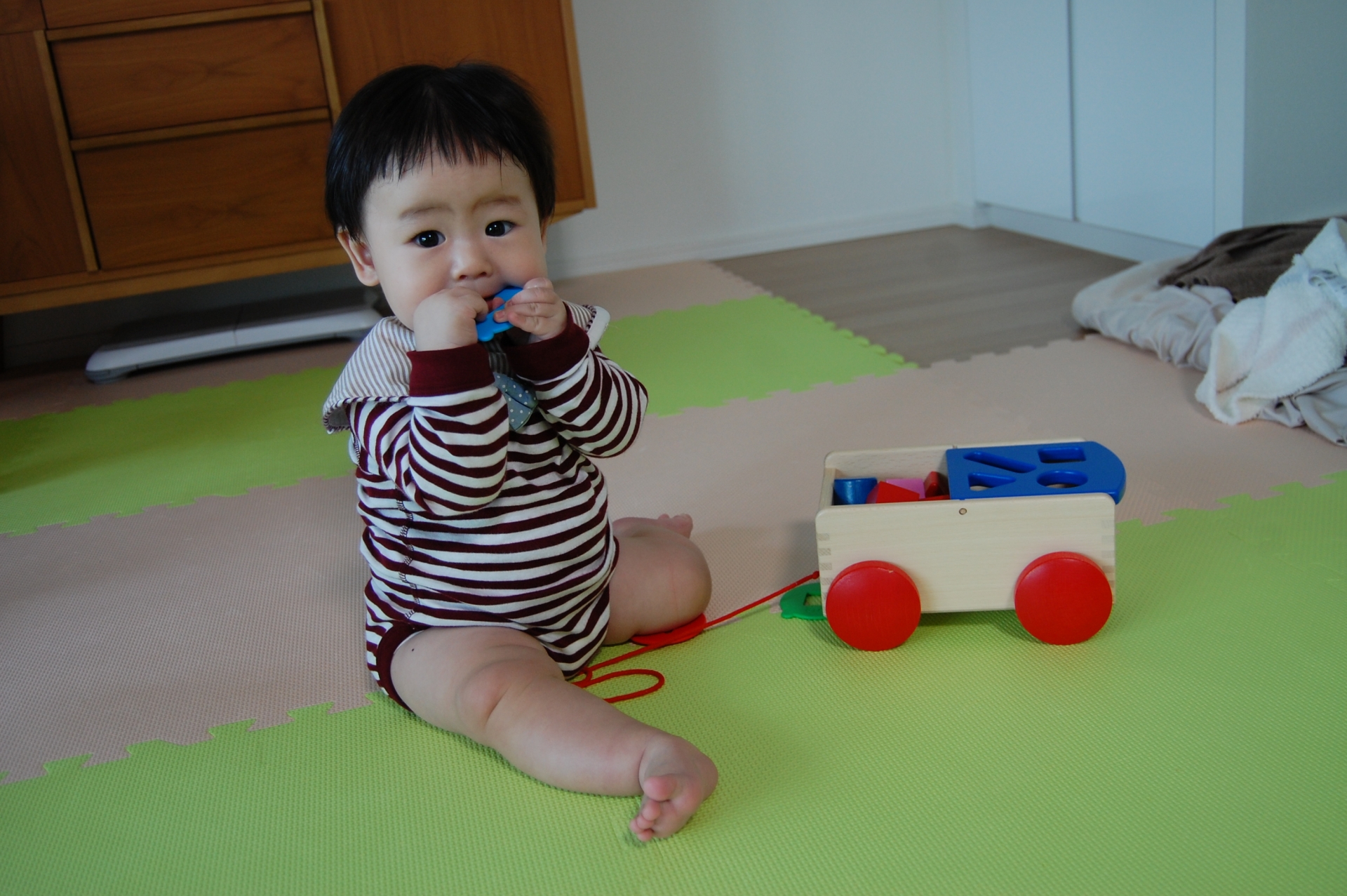 口におもちゃを入れる子ども