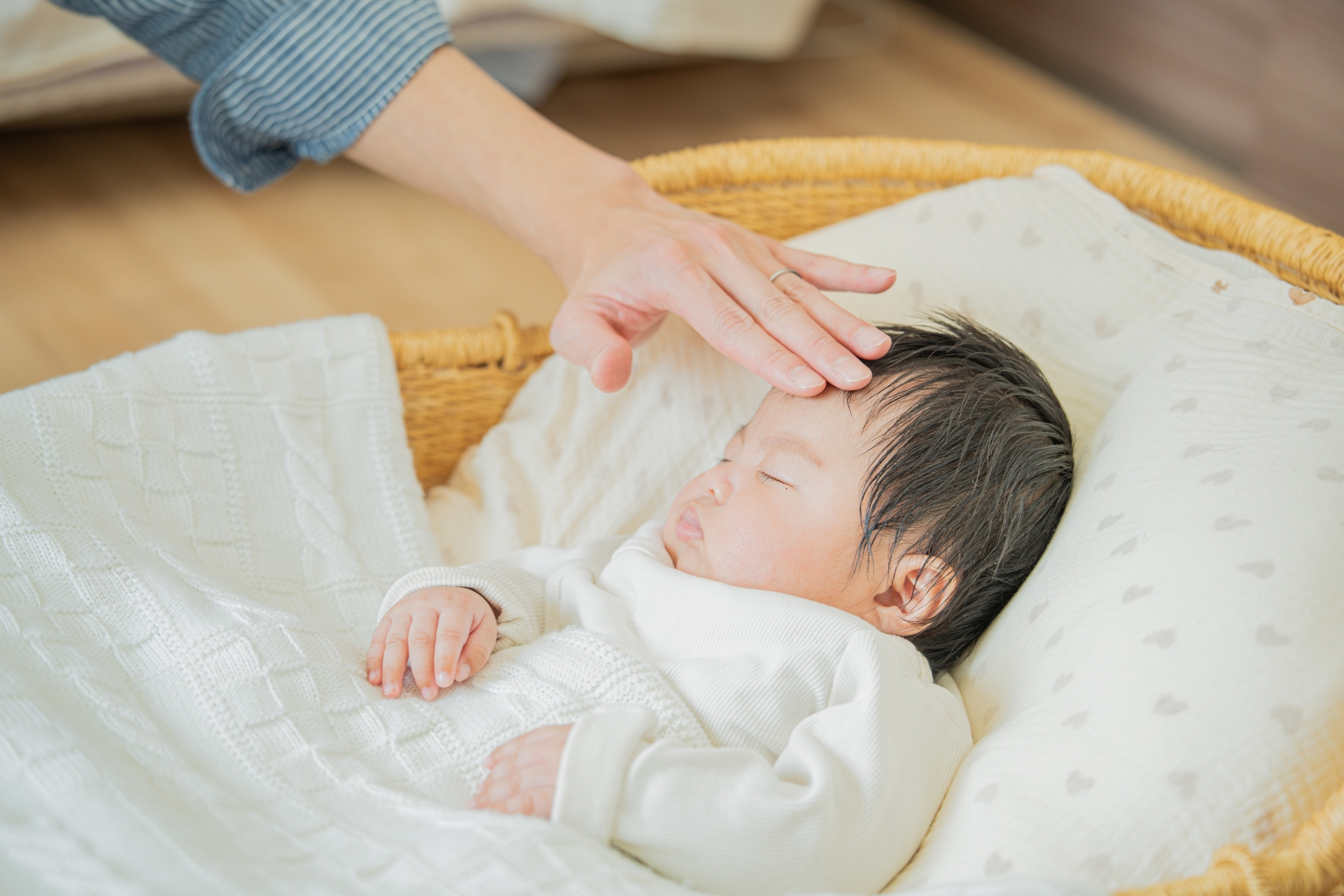 赤ちゃんのおでこに手を当てるママ