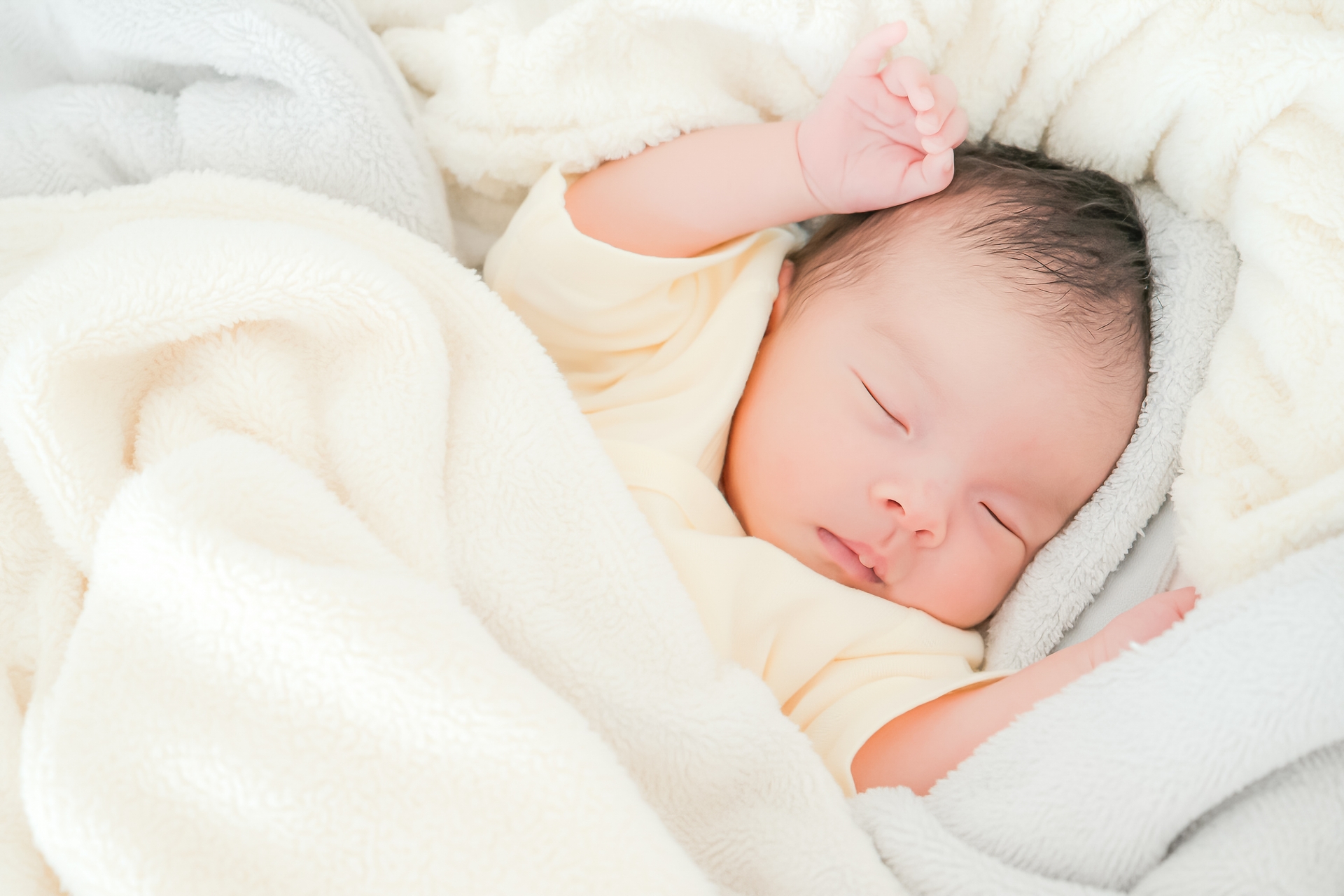 手を上げて寝る赤ちゃん