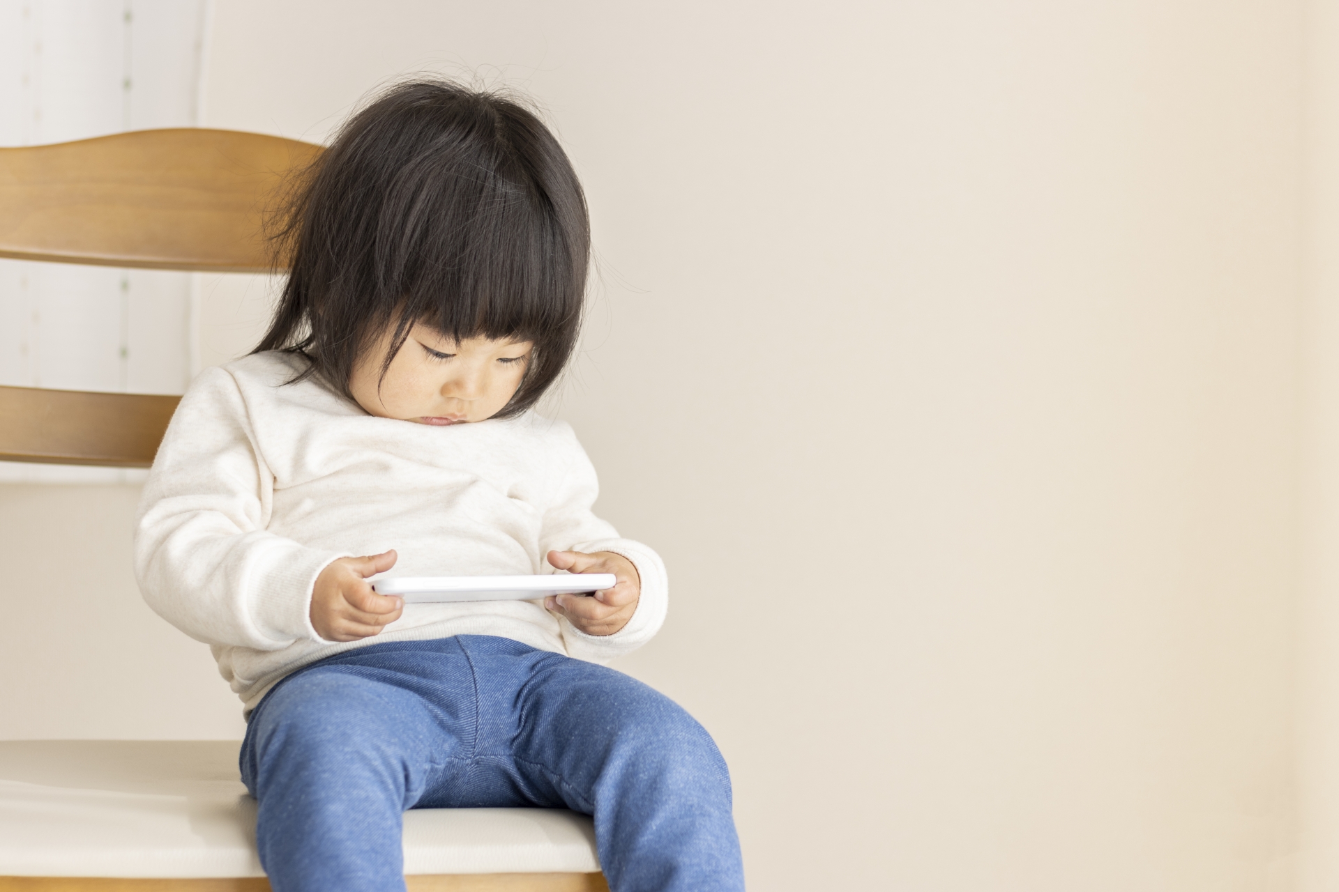 座ってスマホをみる子ども